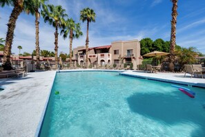 A swimming pool with lounge chairs and palm trees, surrounded by a building with a red roof. - Work + Relax Poolside! Nurse-Ready Glendale Rental (Glendale)