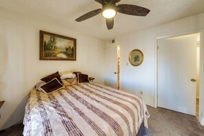A bedroom with a bed, a ceiling fan, a painting, a door, and a mirror. - Work + Relax Poolside! Nurse-Ready Glendale Rental (Glendale)