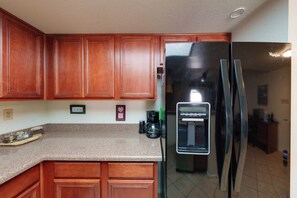 A kitchen with wooden cabinets, a granite countertop, a black refrigerator, and a coffee maker. - Work + Relax Poolside! Nurse-Ready Glendale Rental (Glendale)