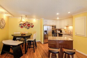 A compact kitchen with white cabinets, a stainless steel refrigerator, and a microwave. - Unwind Poolside, Walk to Shore! Port Aransas Condo (Port Aransas)