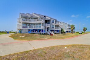 A multi-story residential building with balconies, a central staircase, and a parking area. - Unwind Poolside, Walk to Shore! Port Aransas Condo (Port Aransas)