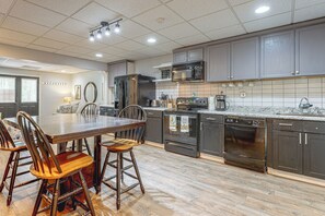 A modern kitchen with a central island, dark cabinetry, and stainless steel appliances. - Wooded Extended Retreat: 15 Mi to Lake Lanier! (Cumming)