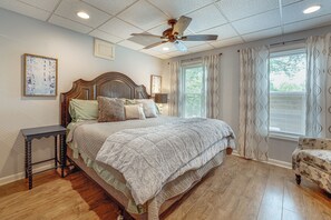 A bedroom with a wooden bed, a nightstand, a ceiling fan, and a window with curtains. - Wooded Extended Retreat: 15 Mi to Lake Lanier! (Cumming)