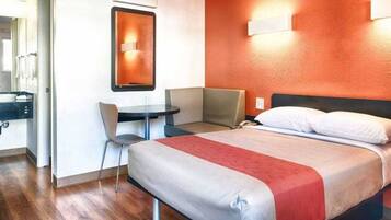 Una habitación de hotel con una cama, un escritorio y una silla.