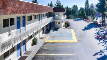 A motel with a parking lot, a small building with a red roof, and a blue sign indicating the number 6.