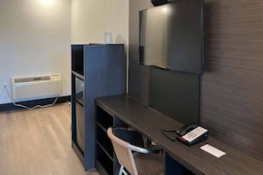 A modern office space with a desk, chair, phone, and a mounted screen. - Spacious King Bed|Free Wifi,Parking (Williams)