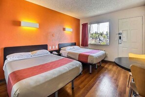 Een hotelkamer met twee bedden, een bureau en een raam met uitzicht.