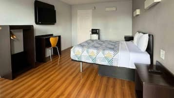 Ein Hotelzimmer mit einem Bett, einem Schreibtisch, einem Stuhl, einem Fernseher und einer Tür.