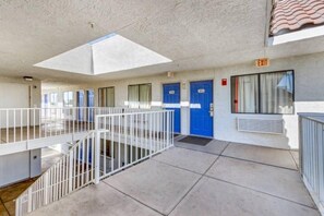 Ein Hotelkorridor mit einer zentralen Treppe, blauen Türen und einem Ausgangsschild.
