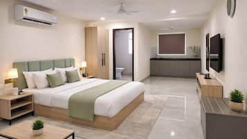 A modern hotel room with a bed, bedside tables, a TV, and a kitchenette.