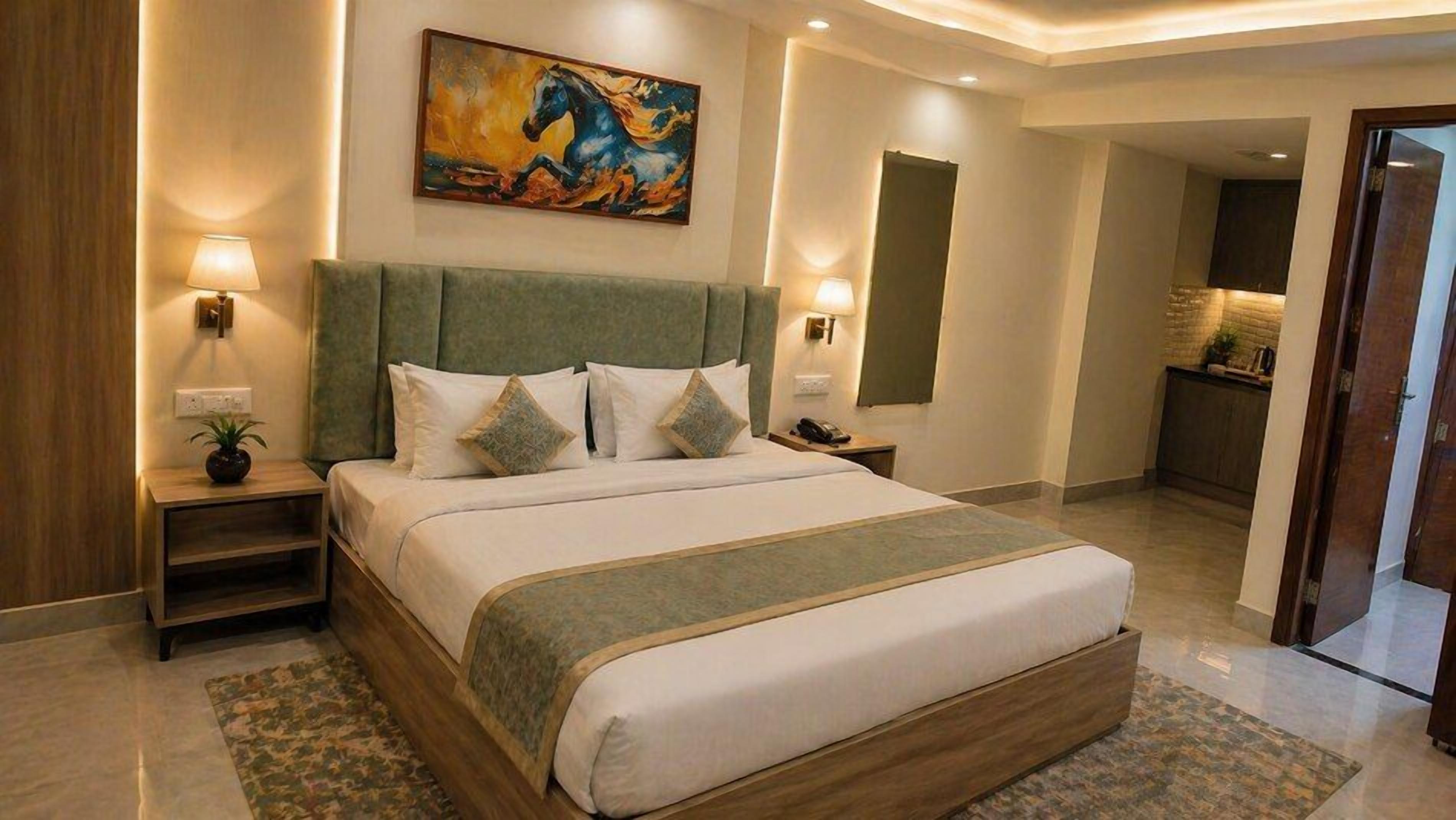 Habitación de hotel con una cama grande, dos mesitas de noche, un cuadro en la pared y vistas al área de la cocina.