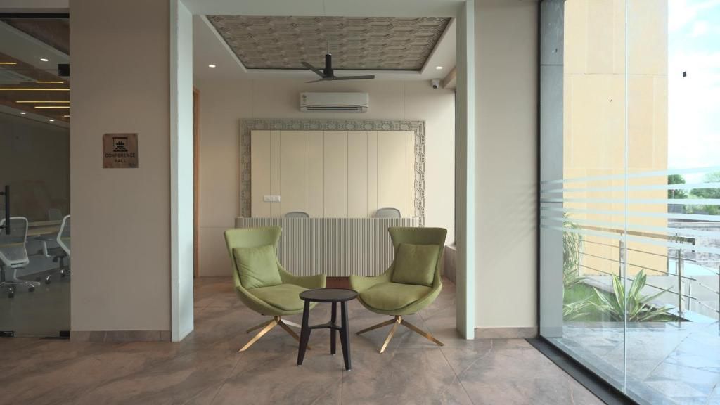 Uma área de recepção com design moderno, com balcão de atendimento, duas poltronas verdes e uma pequena mesa.