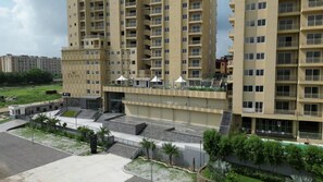 A multi-story residential building with balconies, a gated entrance, and a landscaped area with trees. - HOTEL GKB MARVEL (Jaipur)