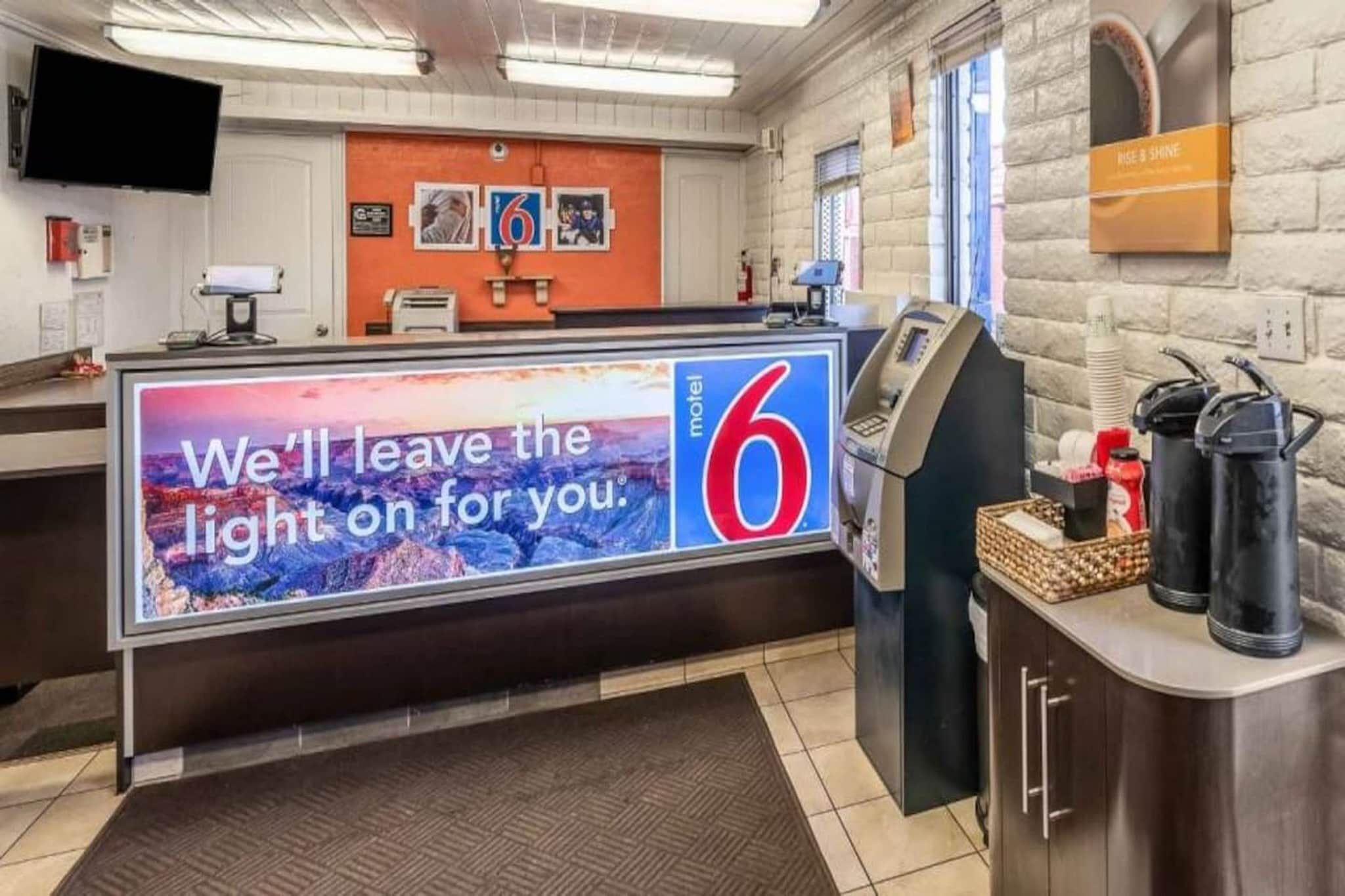 A hotel reception area with a large sign reading 'We'll leave the light on for you.' and a number '6' indicating the motel.
