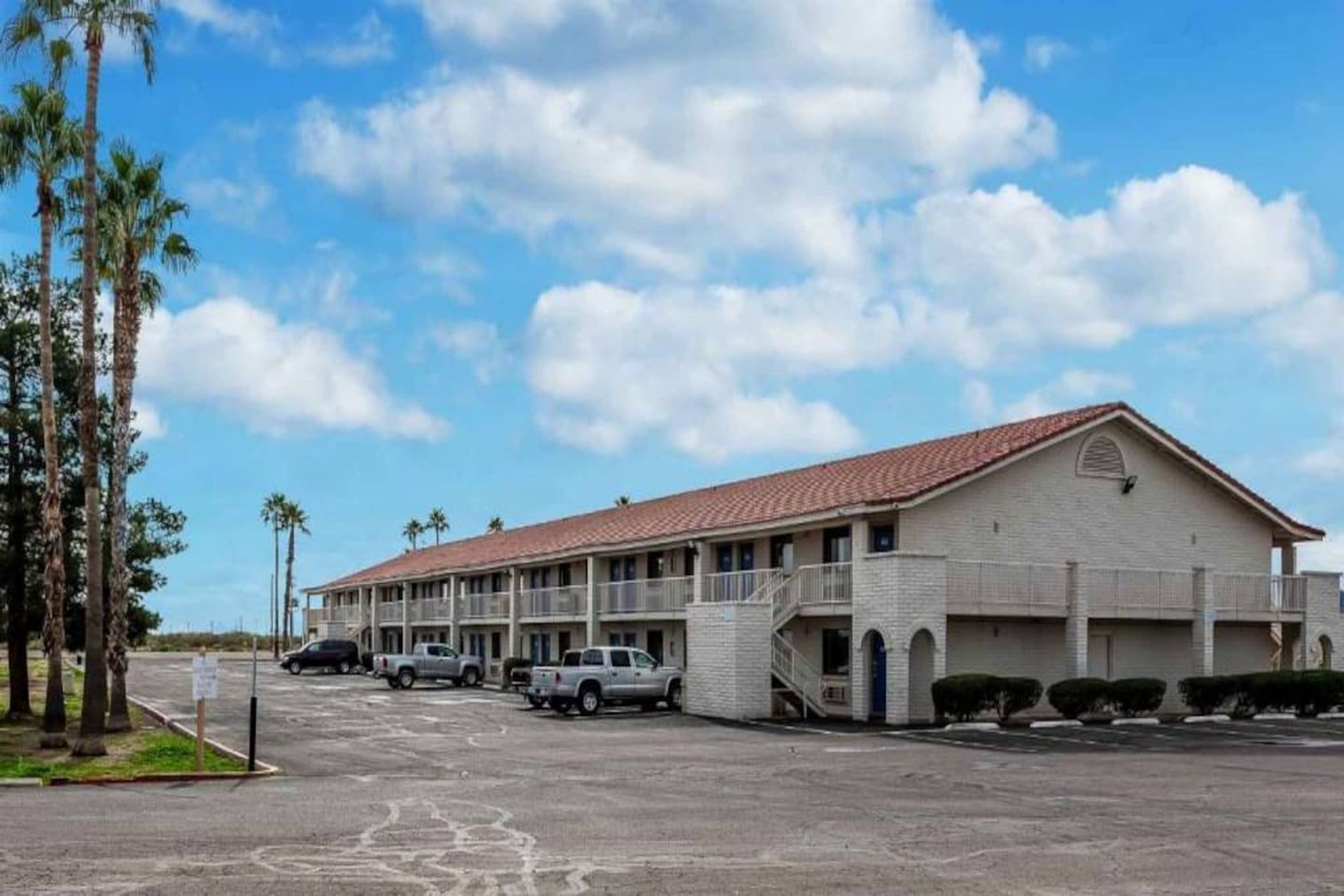 A motel with a two-story structure, a parking lot, and a clear sky.