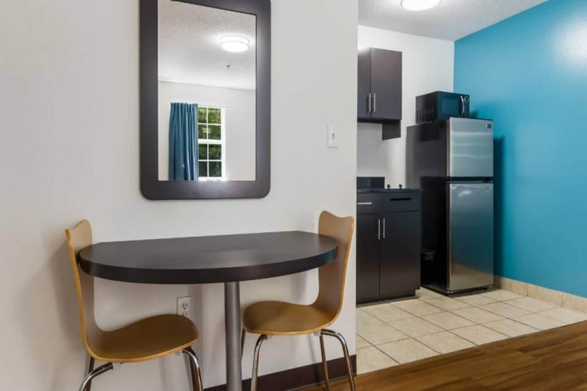 A compact kitchen with a refrigerator, cabinets, and a blue wall.
