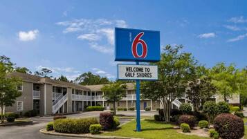 Une enseigne de motel avec le chiffre 6 et une pancarte d’accueil pour Gulf Shores.