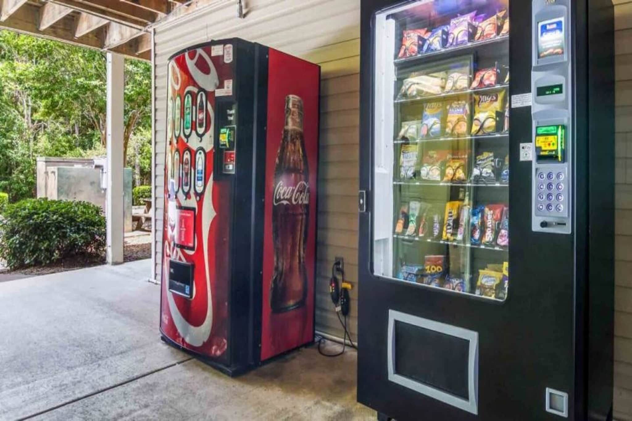 A vending machine with snacks and a Coca-Cola branded machine with a red and black design.