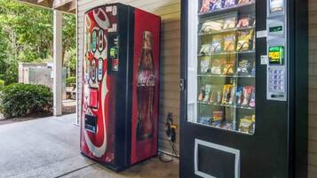 A vending machine with snacks and a Coca-Cola branded machine with a red and black design.