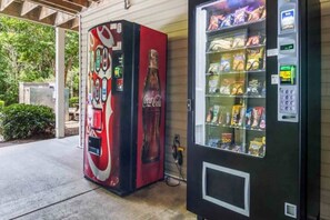Una máquina expendedora con aperitivos y una máquina de Coca-Cola con diseño rojo y negro.