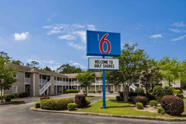 Señal de motel con el número 6 y un cartel de bienvenida a Gulf Shores.