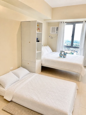 A bedroom with two beds, a wardrobe, and a window with a view. - Inside It park Condo unit Cebu City accessible all (Cebu City)