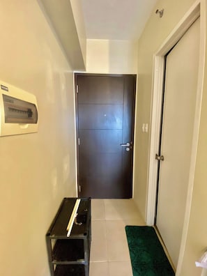 A hallway with a dark door, a small table with a tray, and a green mat at the entrance. - Inside It park Condo unit Cebu City accessible all (Cebu City)