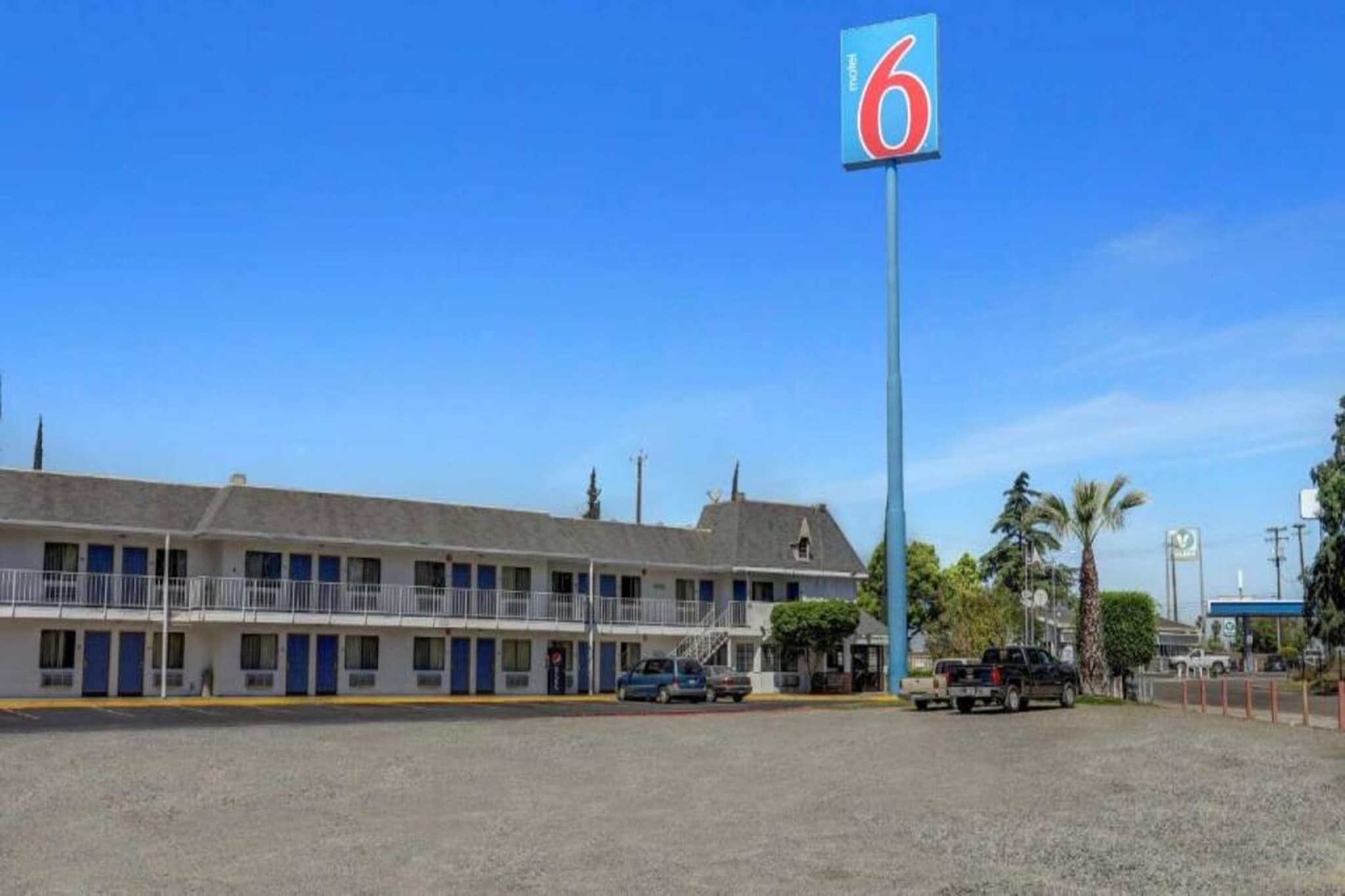A motel with a prominent '6' sign, a parking lot, and a building with multiple windows and balconies.