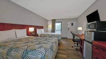Habitación de hotel con dos camas, un escritorio, una silla, un televisor y un refrigerador.