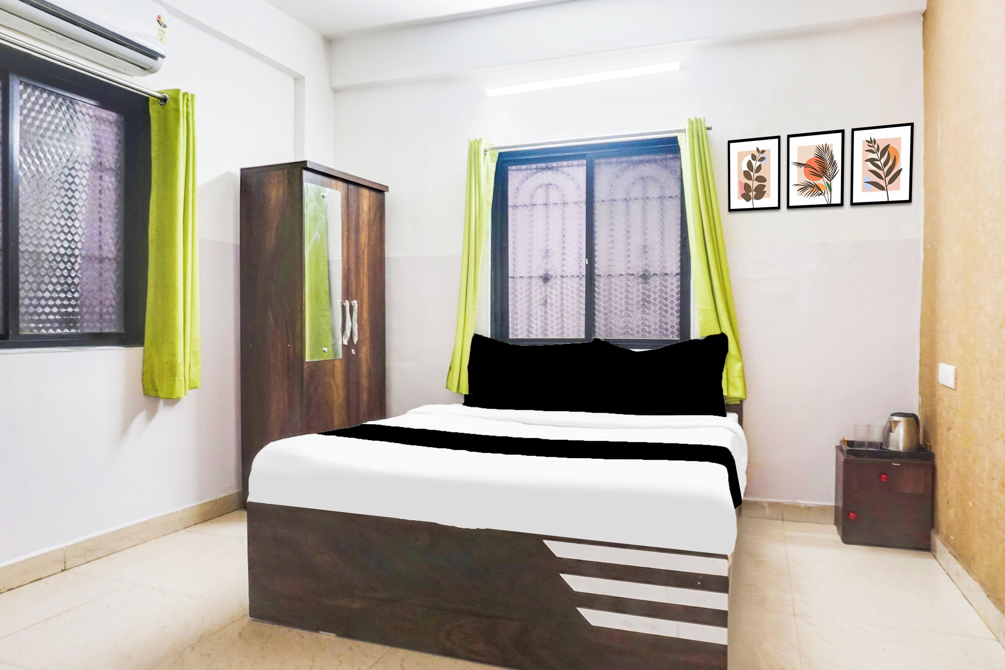Une chambre à coucher avec un lit, une armoire, une fenêtre avec des rideaux et un mur orné de tableaux.
