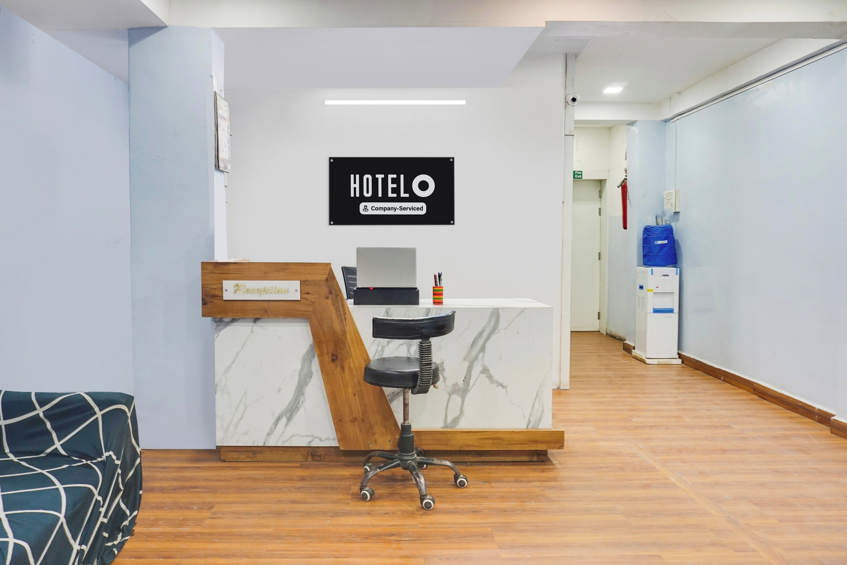 En hotelreception med bordplade i marmor, receptionsskilt og en receptionsstol.