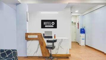 En hotelreception med bordplade i marmor, receptionsskilt og en receptionsstol.