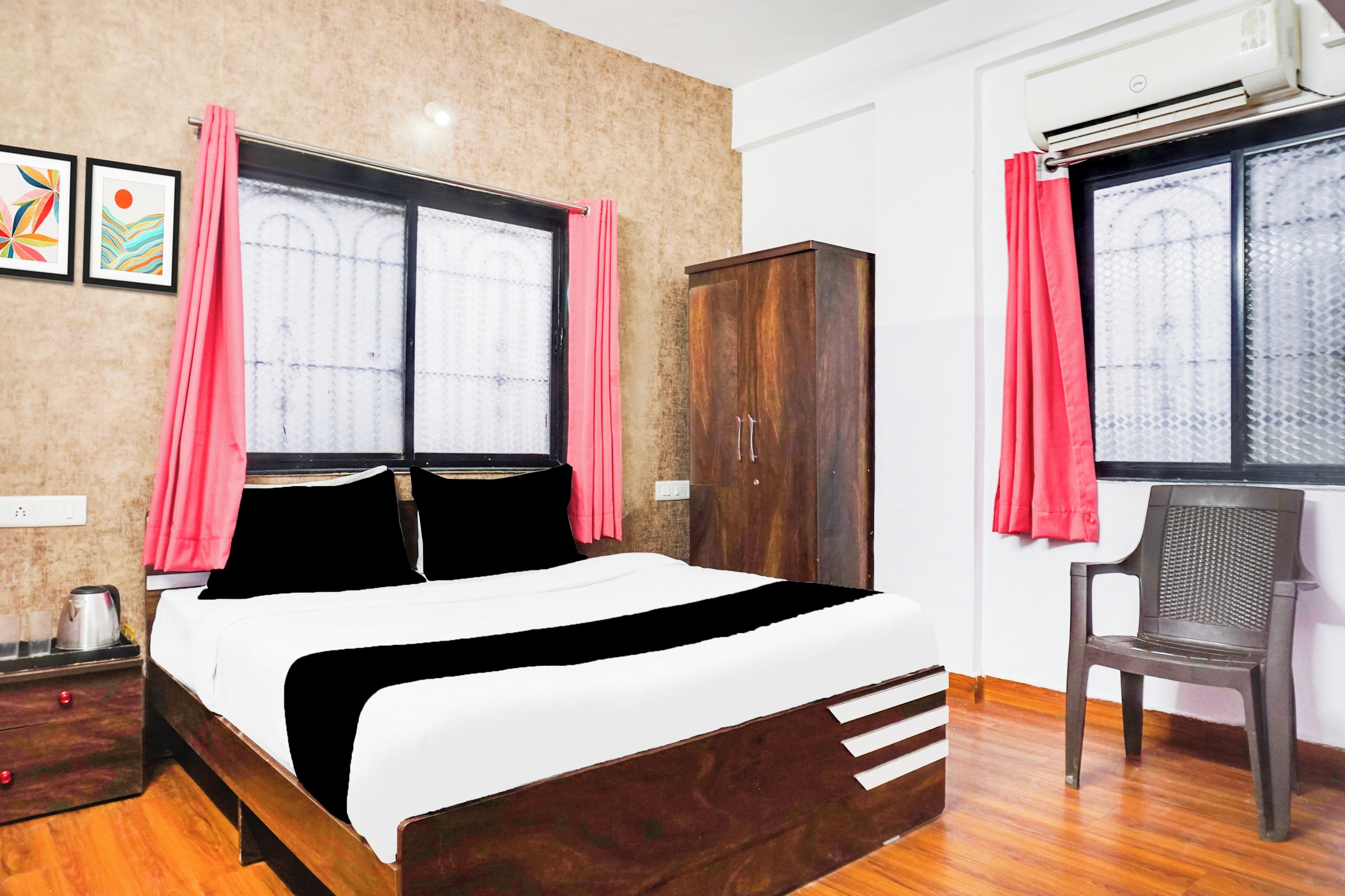 Un dormitorio con una cama, un armario, una silla y dos ventanas con cortinas.