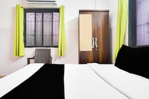Quarto de hotel com cama, escrivaninha e guarda-roupa.