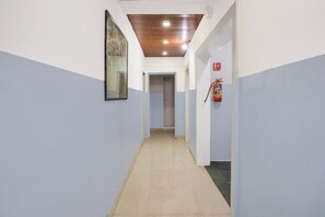 A corridor with a fire extinguisher mounted on the wall, a door at the end, and a ceiling with recessed lighting. - Hotel O Season Inn (Paud)