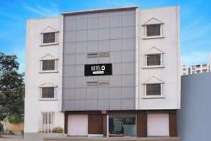 Um edifício moderno de hotel com uma placa indicando 'HOTELO Company Serviced'.