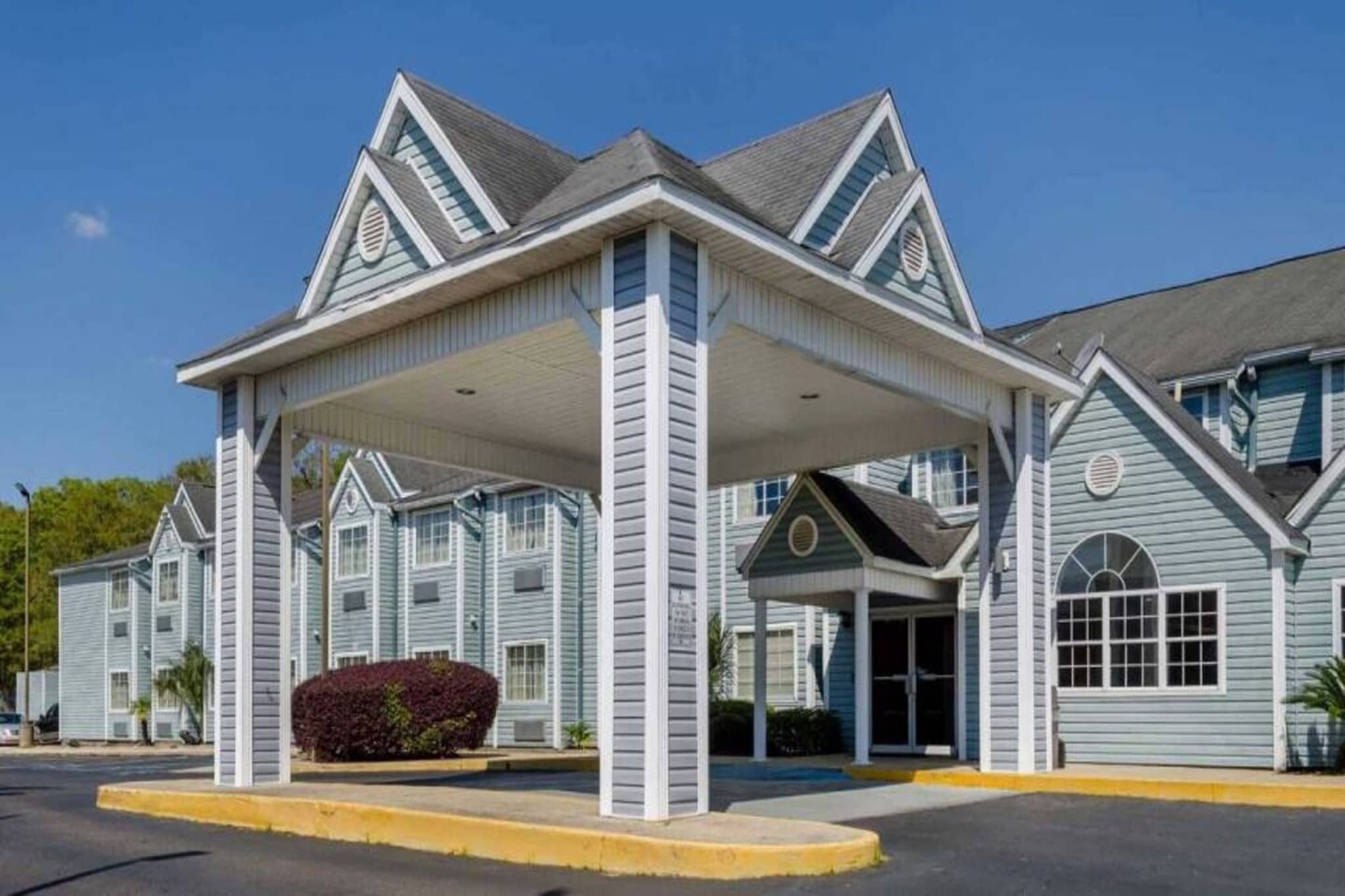 Un hotel con ingresso coperto, diverse finestre e una facciata simmetrica.