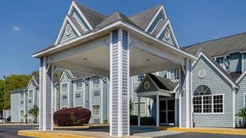 Un hotel con ingresso coperto, diverse finestre e una facciata simmetrica.