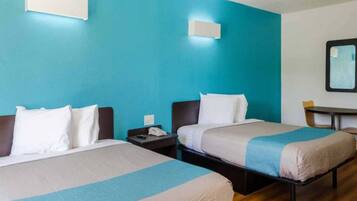 Una camera d'albergo con due letti, un comodino, una scrivania e uno specchio.