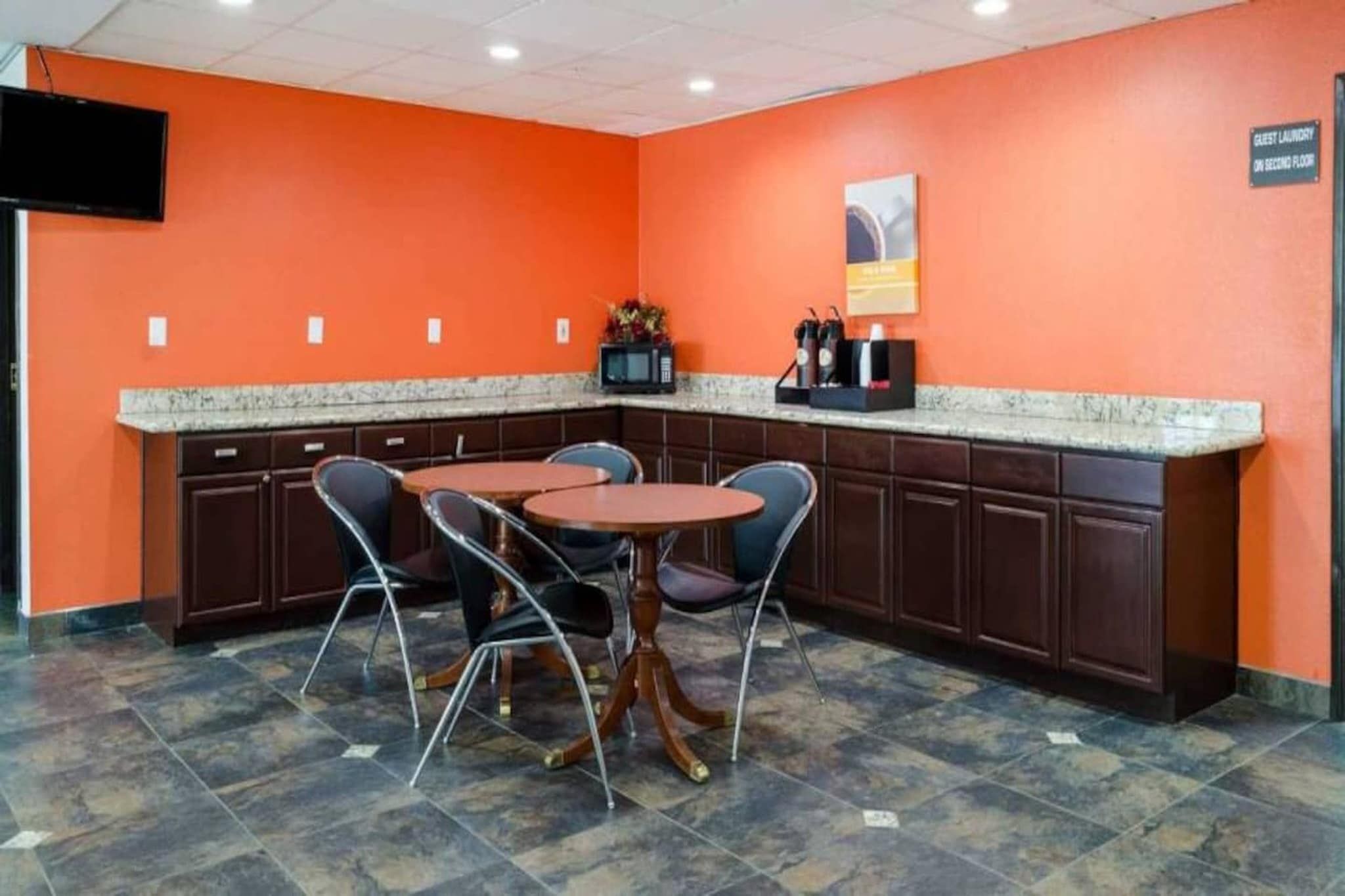 A restaurant area with a round table and chairs, a microwave, and a coffee machine on the counter.