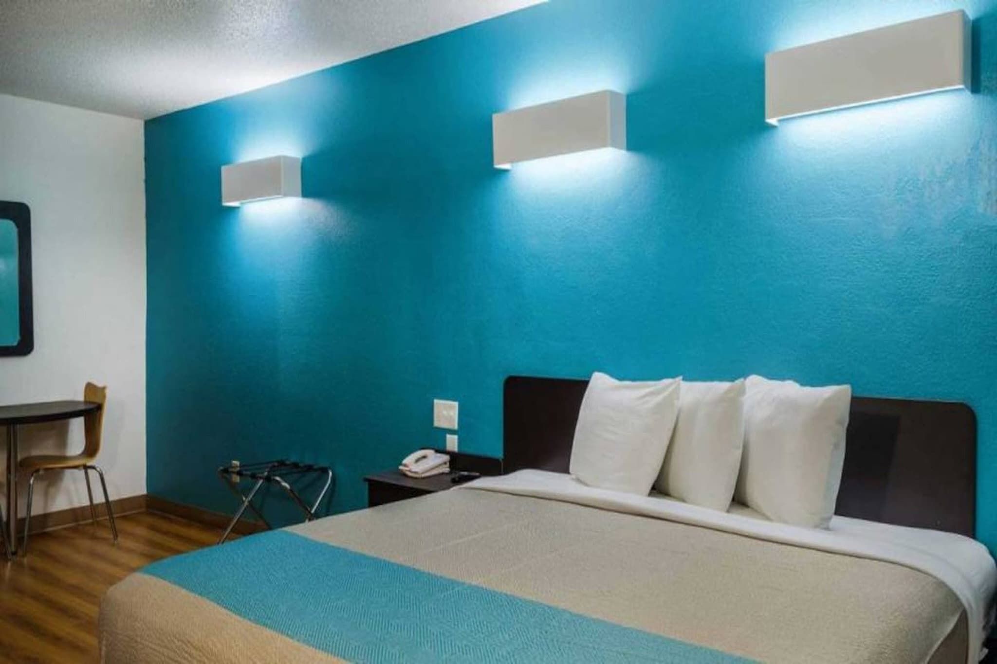 A hotel room with a bed, a desk, a chair, and a telephone.