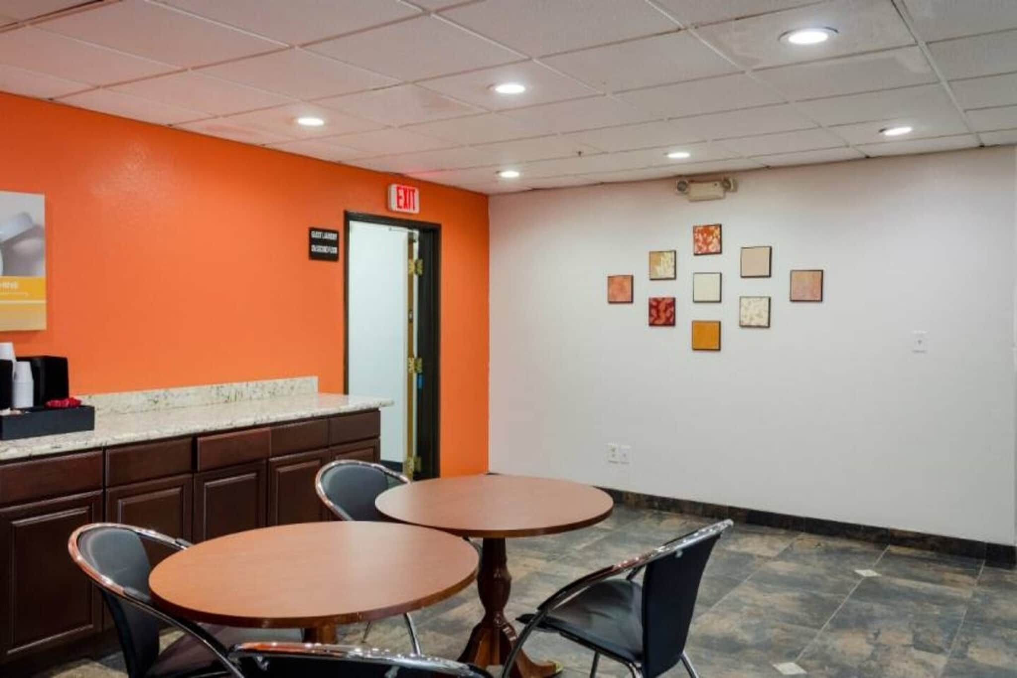 A hotel lobby with a reception desk, two round tables, and chairs.