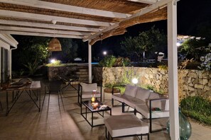 An outdoor patio with a stone wall, seating area, and hanging light fixture. - Capovillas - Country Villa Armonia with privat pool (zambrone)