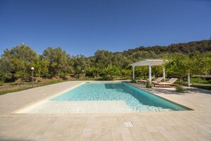 A rectangular swimming pool with a tiled deck, surrounded by trees and a pergola with lounge chairs. - Capovillas - Country Villa Armonia with privat pool (zambrone)