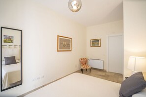 A hotel room with a bed, a chair, a radiator, a door, and framed pictures on the wall. - Capovillas - Country Villa Armonia with privat pool (zambrone)