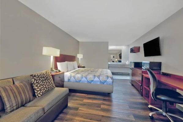 Een hotelkamer met een bed, een bureau, een stoel, een bank en een televisie.