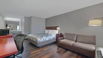 A hotel room with a bed, a sofa, a desk, and a chair.