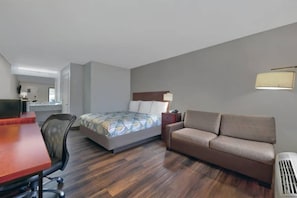 A hotel room with a bed, a sofa, a desk, and a chair.
