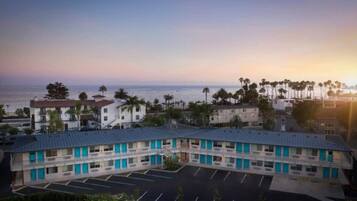 Um motel com estacionamento, piscina e vista para o mar.