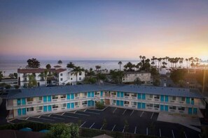 Um motel com estacionamento, piscina e vista para o mar.